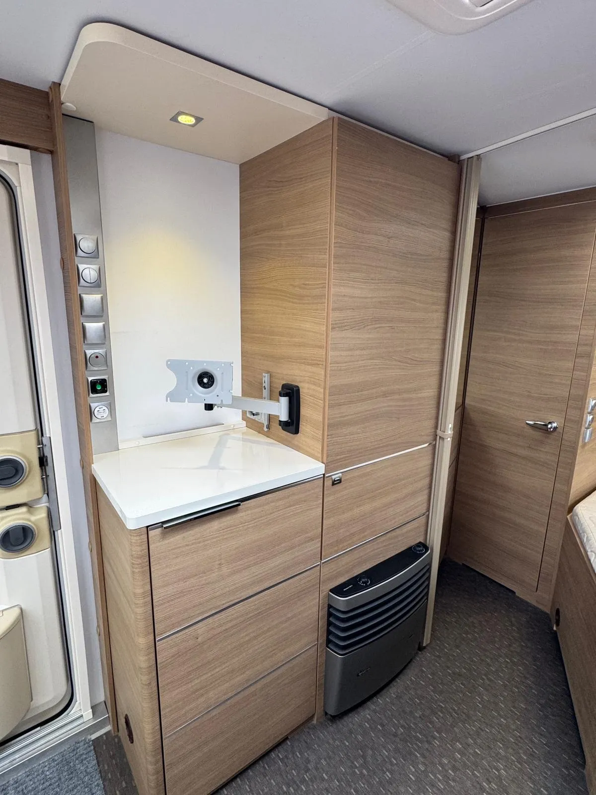 Obrázek interiéru obytného auta s dřevěnými skříňkami a moderními spotřebiči. Design jako Laika.