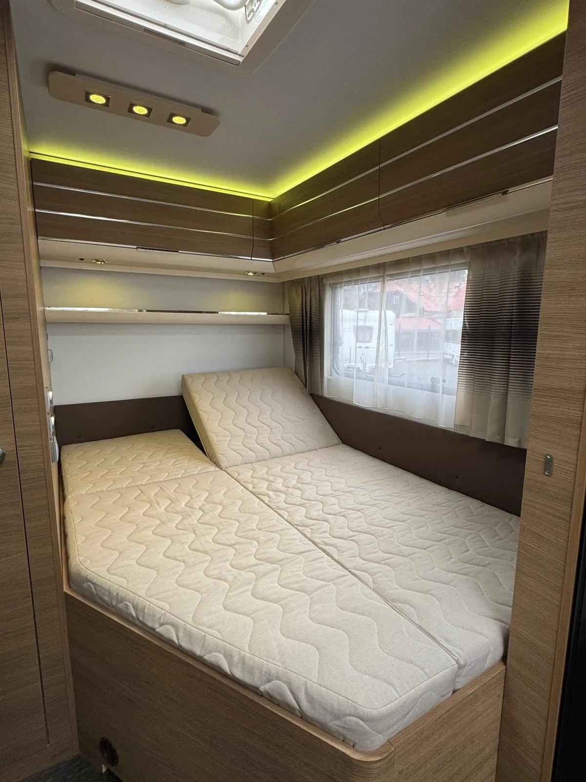 Obrázek ukazuje moderní interiér karavanu s pohodlnými lůžky a atmosferickým osvětlením.