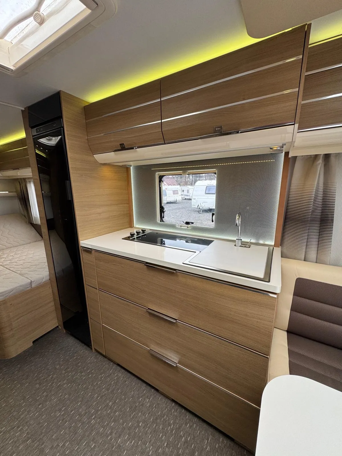 Interiér obytného auta s moderní kuchyňkou a komfortním posezením. Vybavení z kvalitního dřeva pro pohodlné cestování.