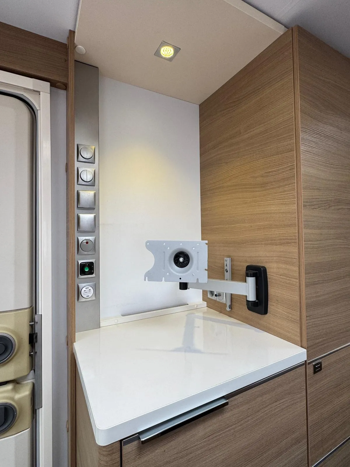 Interiér moderního karavanu s kuchyňskou linkou a televizním držákem. Stylové dřevěné provedení.