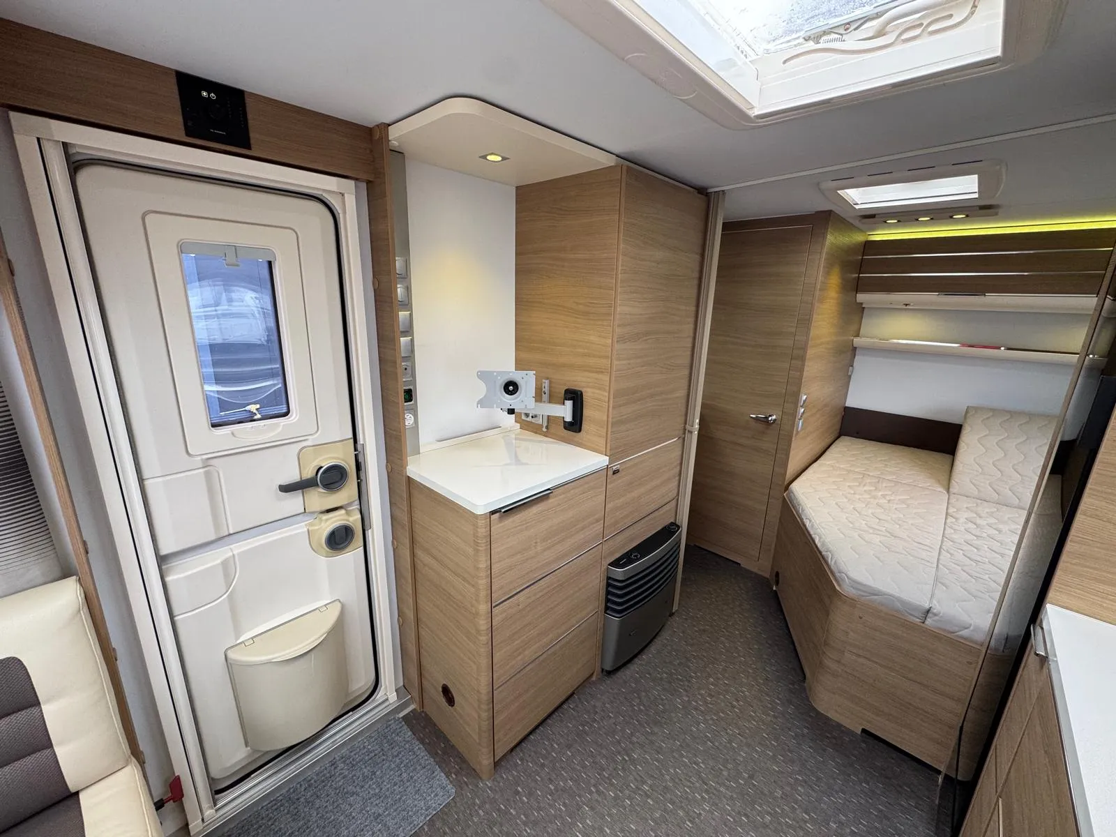 Interiér moderního obytného auta s kuchyňkou a úložným prostorem. Elegantní design a funkční uspořádání.