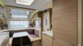 Interiér karavanu s moderním uspořádáním a kuchyňským koutem. Ideální pro pohodové cestování.