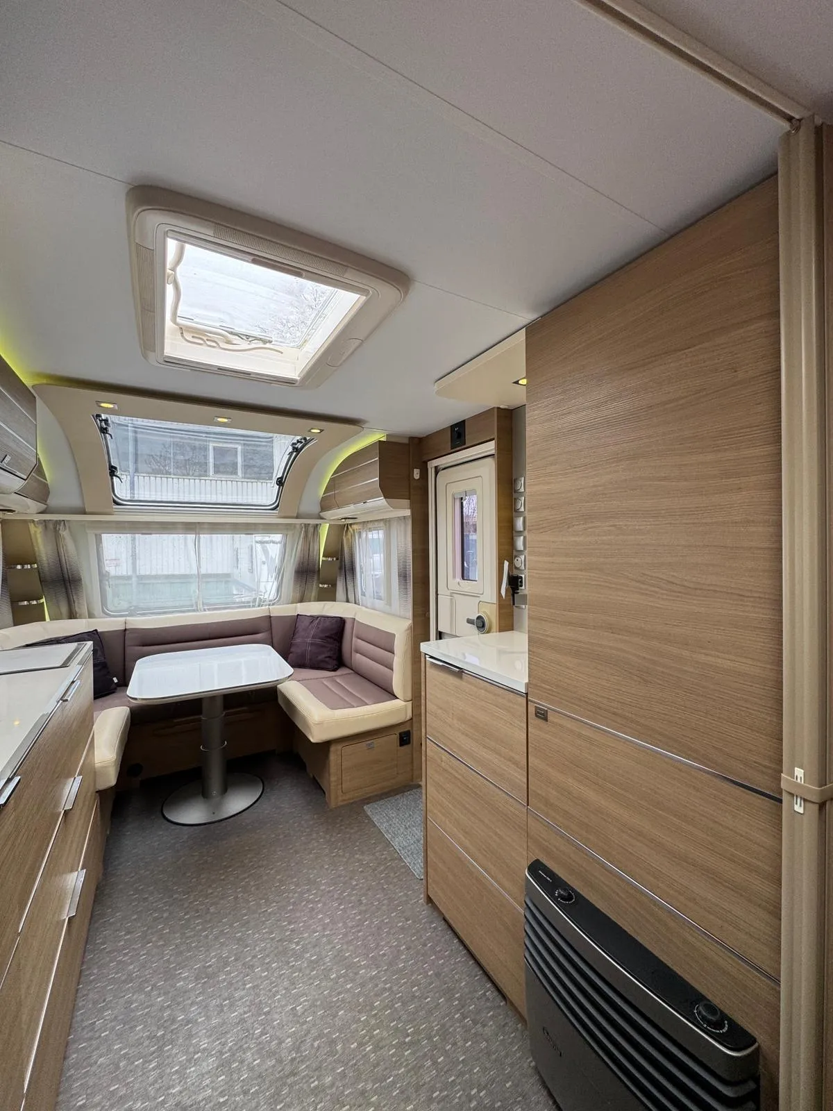 Interiér karavanu s moderním uspořádáním a kuchyňským koutem. Ideální pro pohodové cestování.