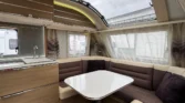 Interiér karavanu s příjemným posezením a kuchyňským koutem. Moderní design a dostatek světla.