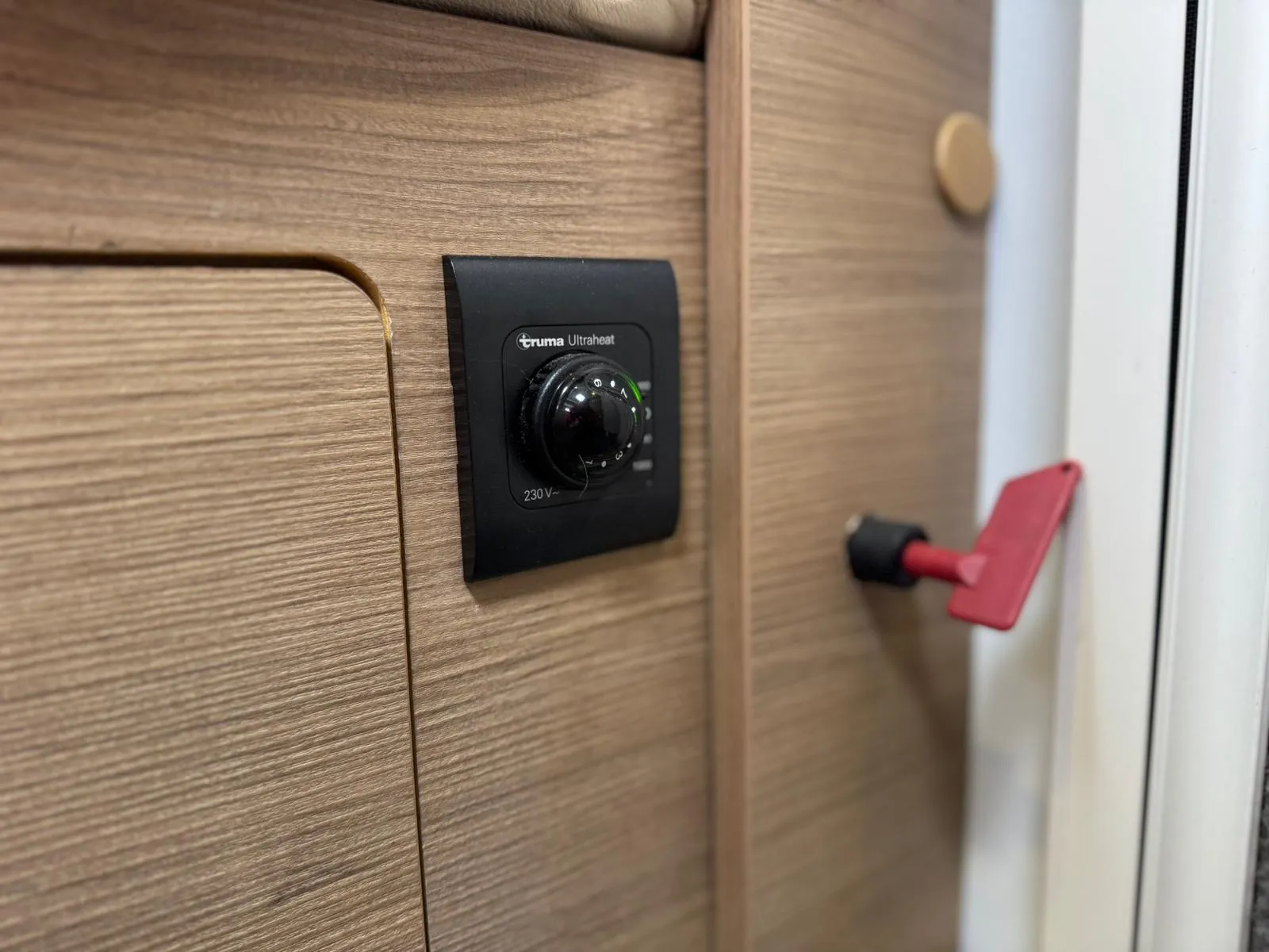 Obrázek ukazuje ovladač Truma Ultraheat v interiéru obytného vozu, ideální pro komfortní kempování.