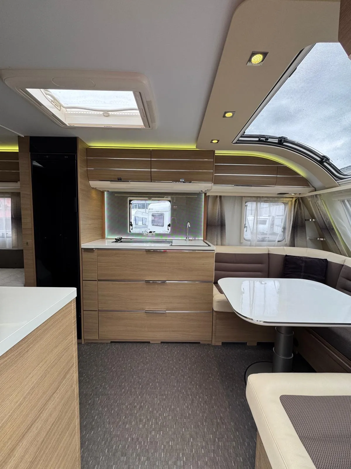 Interiér karavanu s moderním designem, kuchyňka a posezení pro pohodlné bydlení na cestách.