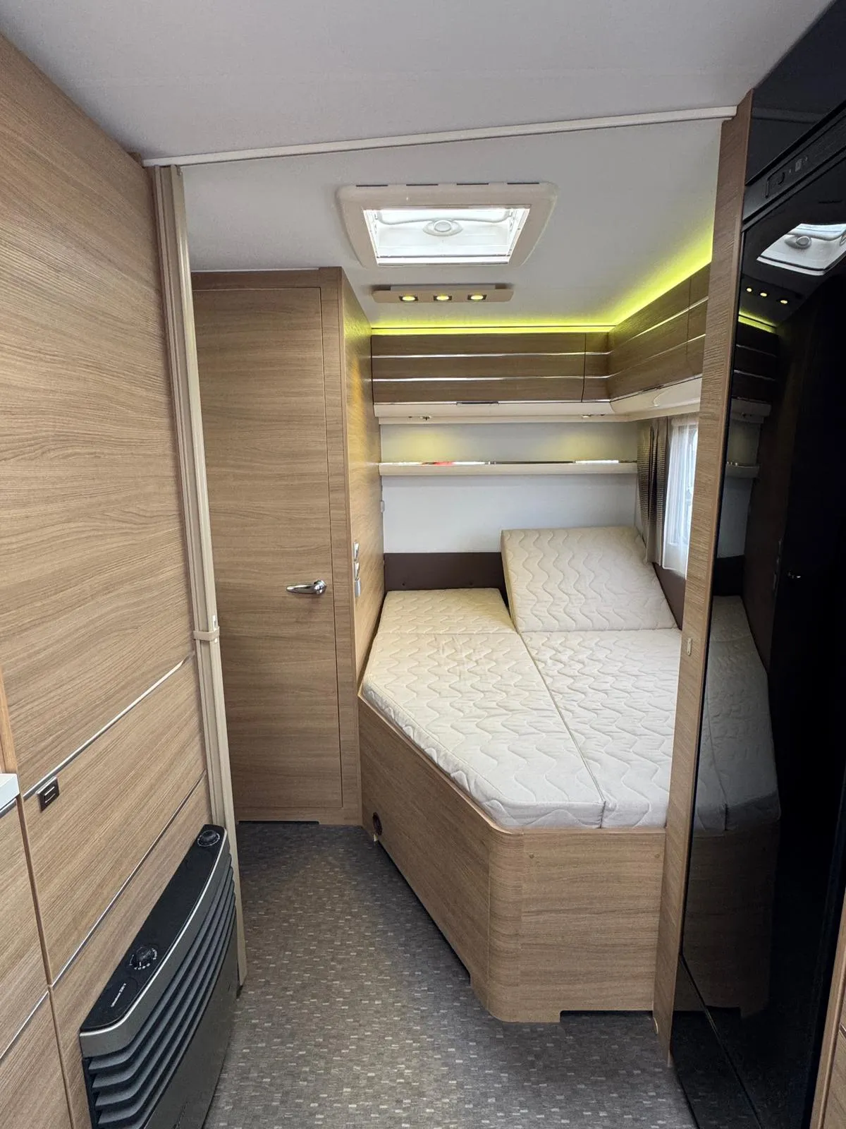 Interiér moderního karavanu s pohodlnými postelemi a dřevěnými obklady. Ideal pro relaxaci na cestách.