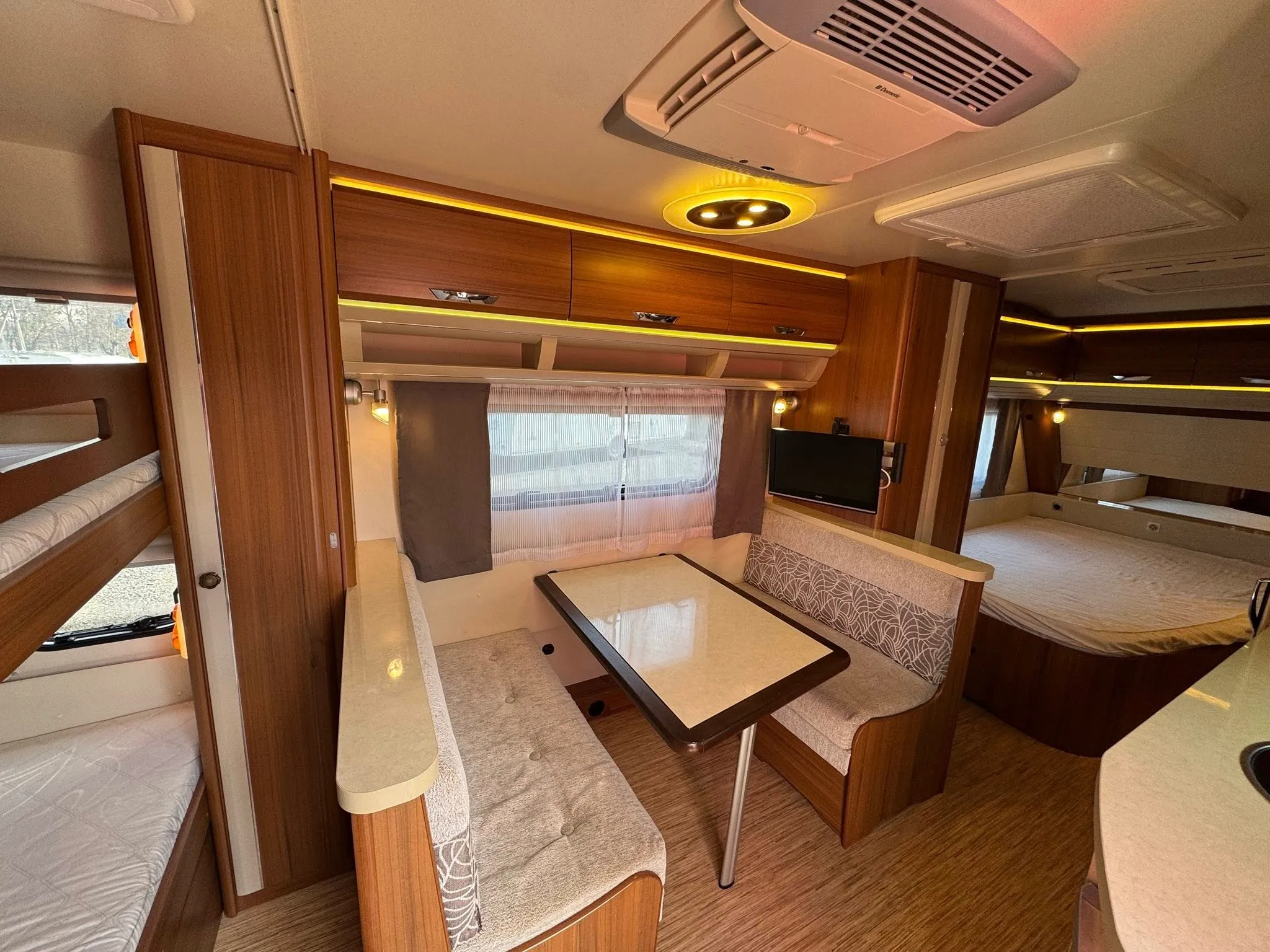 Interiér obytného auta s moderním designem, pohodlnou sedací soupravou a spacími oblastmi. Ideální pro cestování.