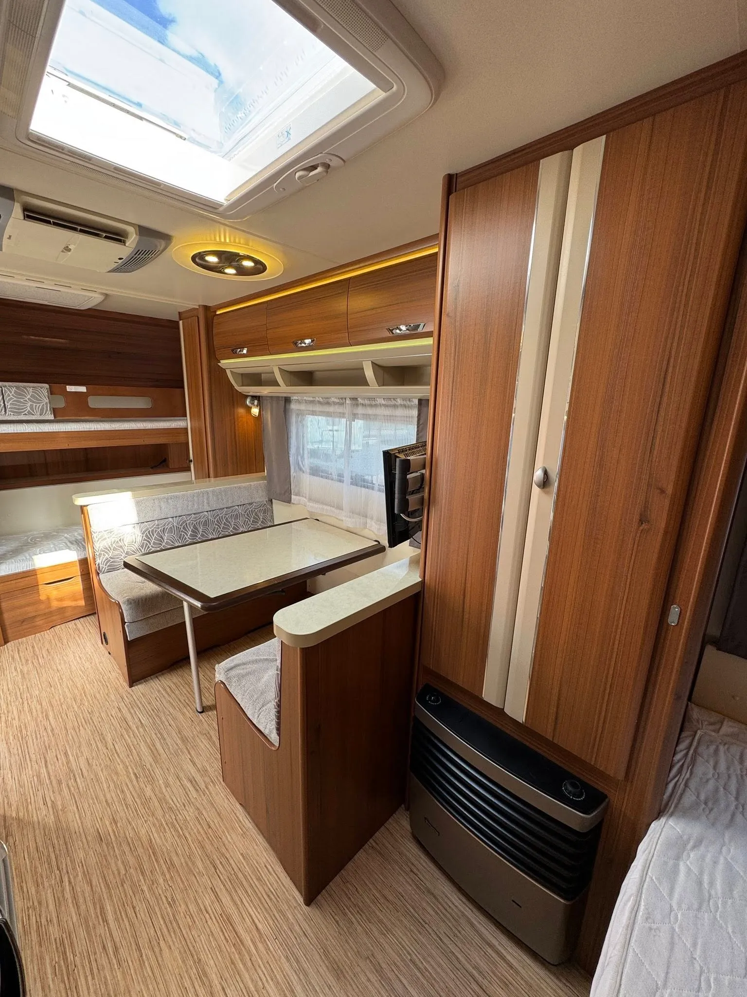 Obrázek interiéru obytného vozu s moderním designem a prostorným posezením. Vhodné pro pohodlné cestování.