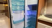 Obrázek představuje lednici v karavanu Hobby, ideální pro uchování potravin během cestování.