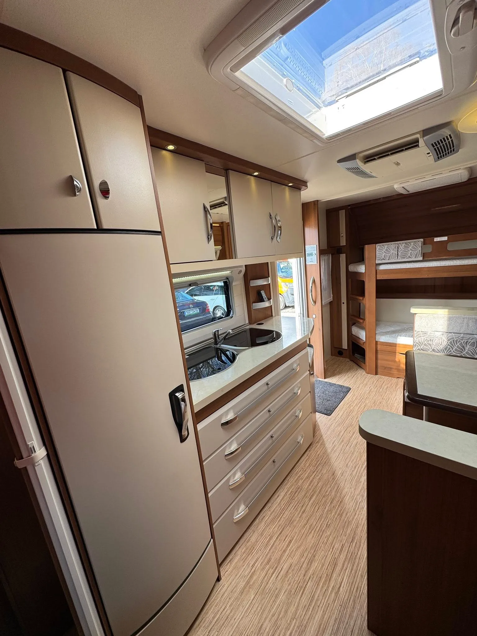 Obytné auto s moderním interiérem, prostor pro vaření a spánek. Elegantní design a funkční úložné prostory.