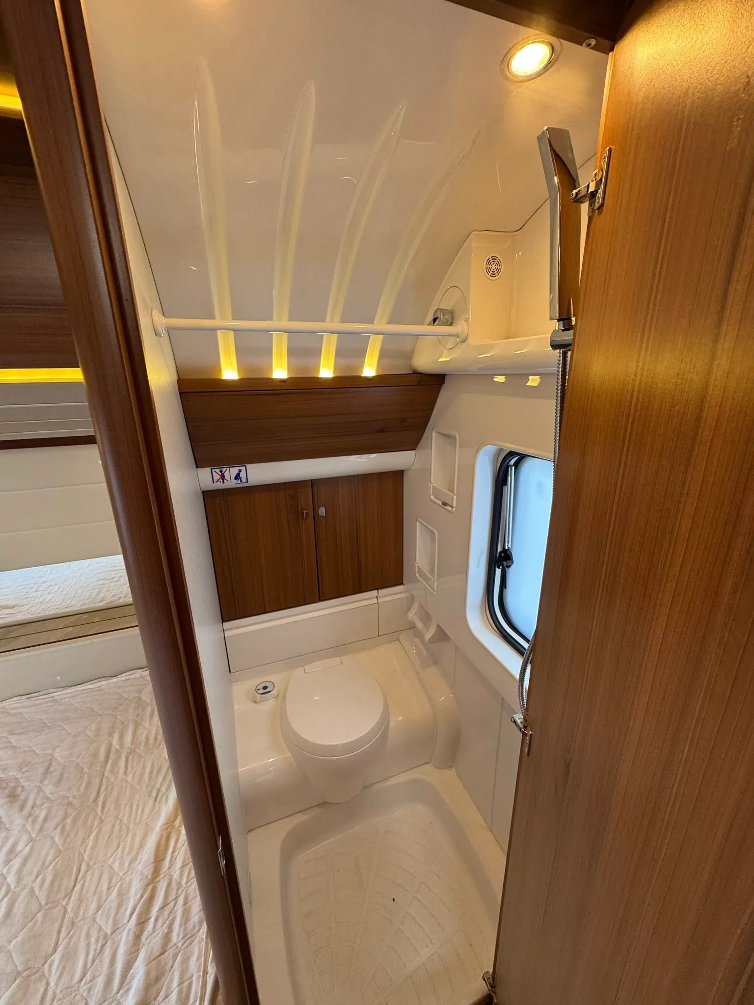 Koupelna v obytném autě s toaletou a sprchou, moderní design a přírodní materiály. Ideální pro komfortní cestování.