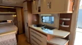 Obrázek interiéru obytného vozu s moderním kuchyňským vybavením a útulným designem.