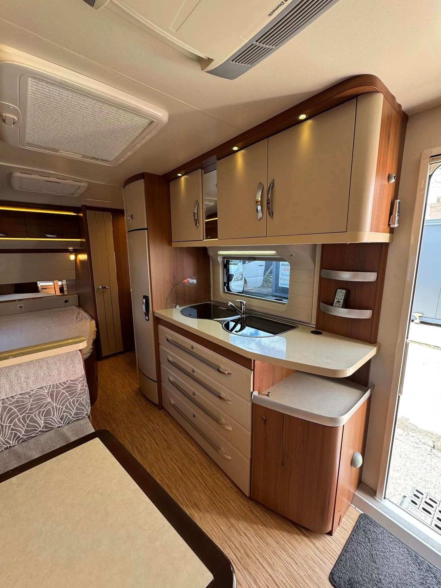 Obrázek interiéru obytného vozu s moderním kuchyňským vybavením a útulným designem.