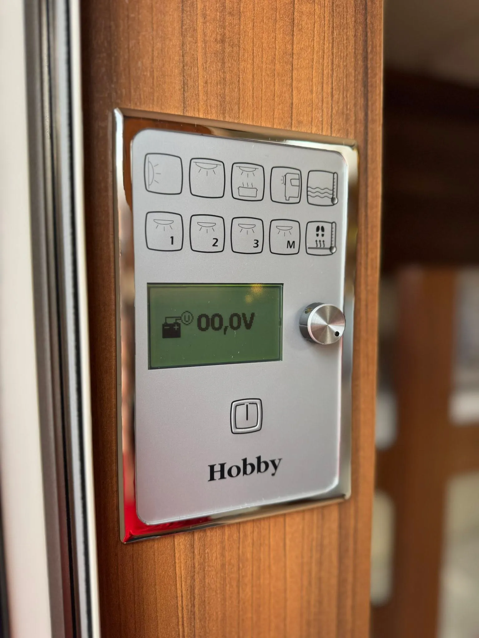 Obrázek zobrazuje ovládací panel obytného vozu Hobby s funkcemi osvětlení a monitorováním.