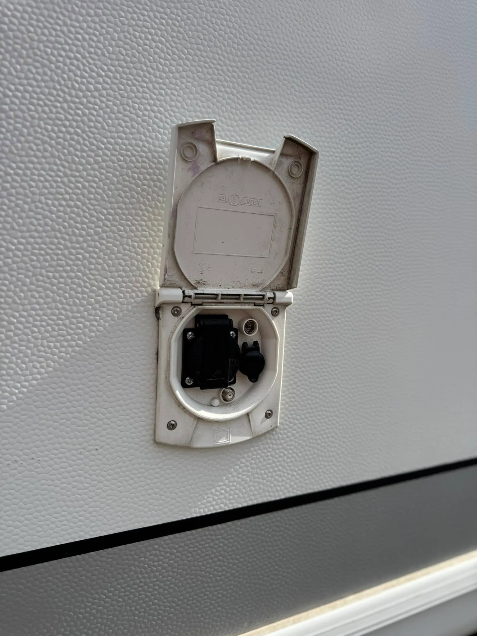 Obrázek zobrazuje zásuvku na karavanu, ideální pro snadné napájení během cestování.