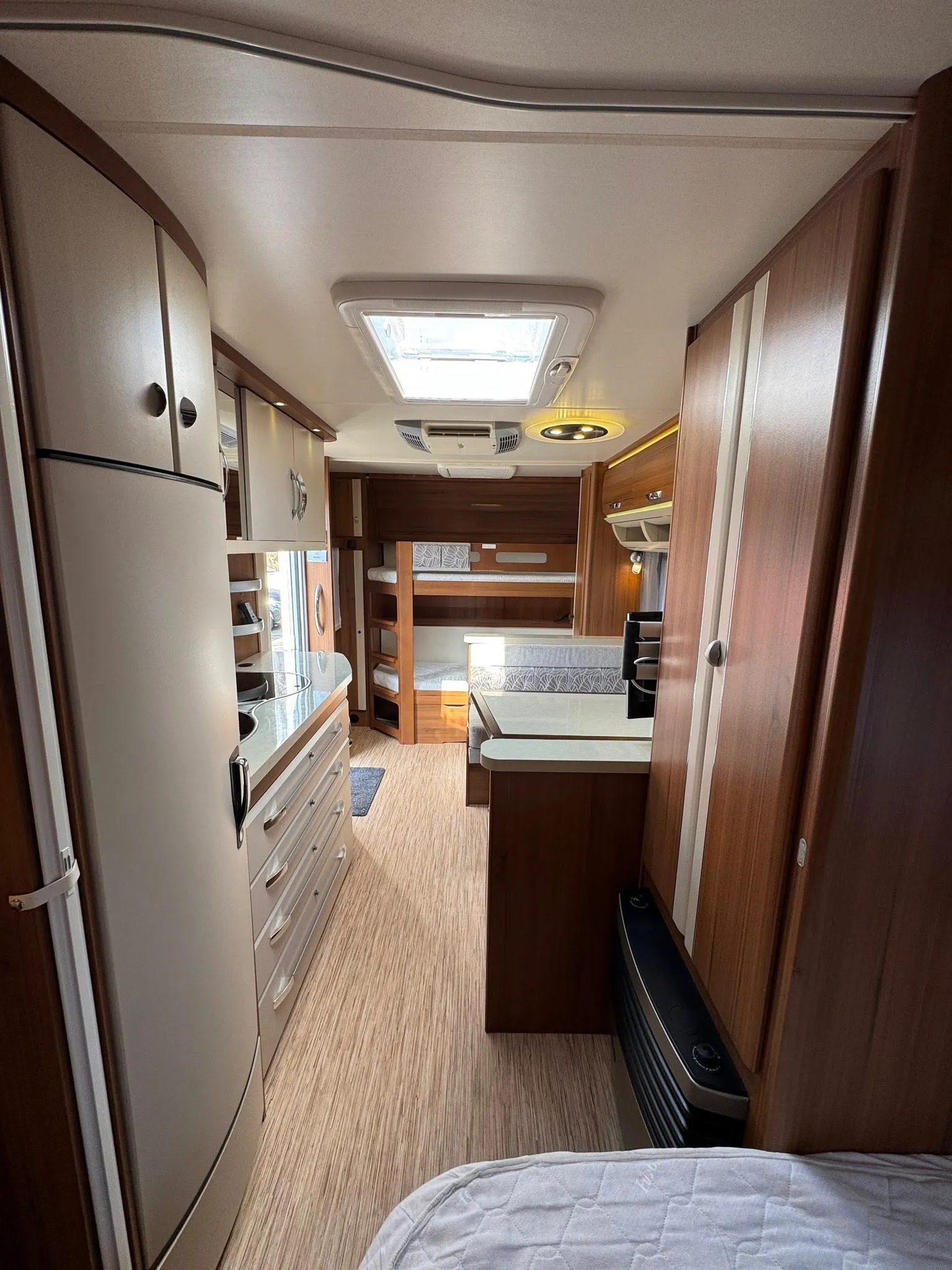 Obrázek interiéru obytného auta, moderní a prostorný s kuchyní a lůžky pro pohodlné cestování.