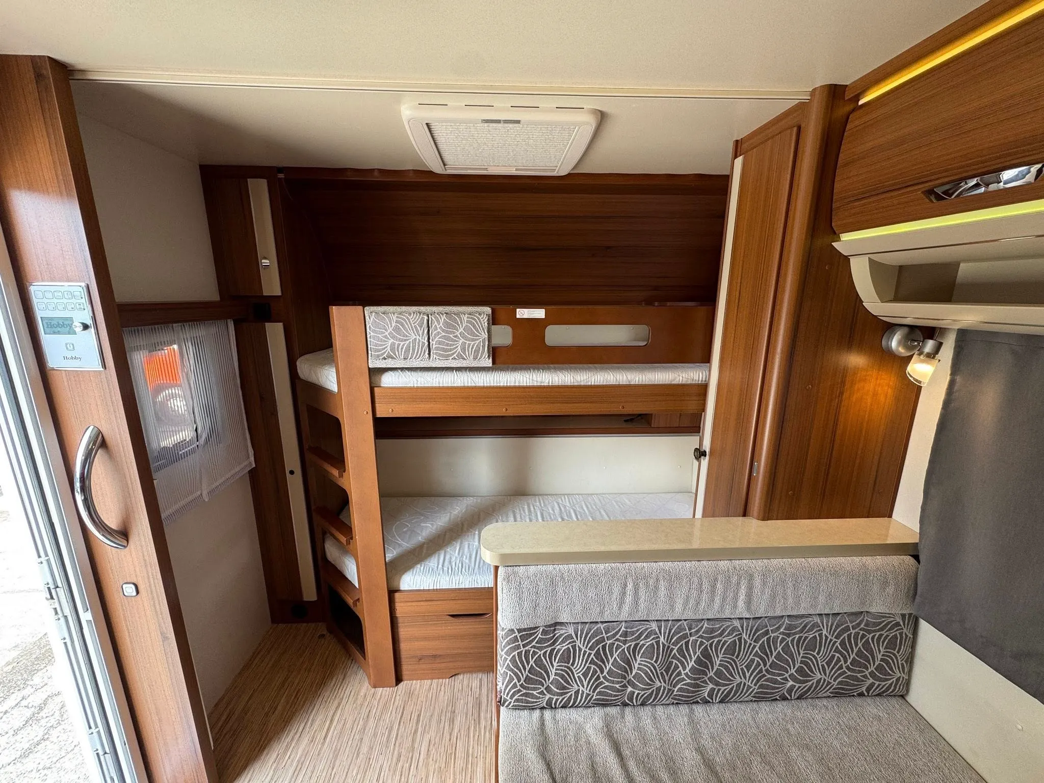 Interiér karavanu Hobby s palandami a útulným posezením pro pohodlné cestování.