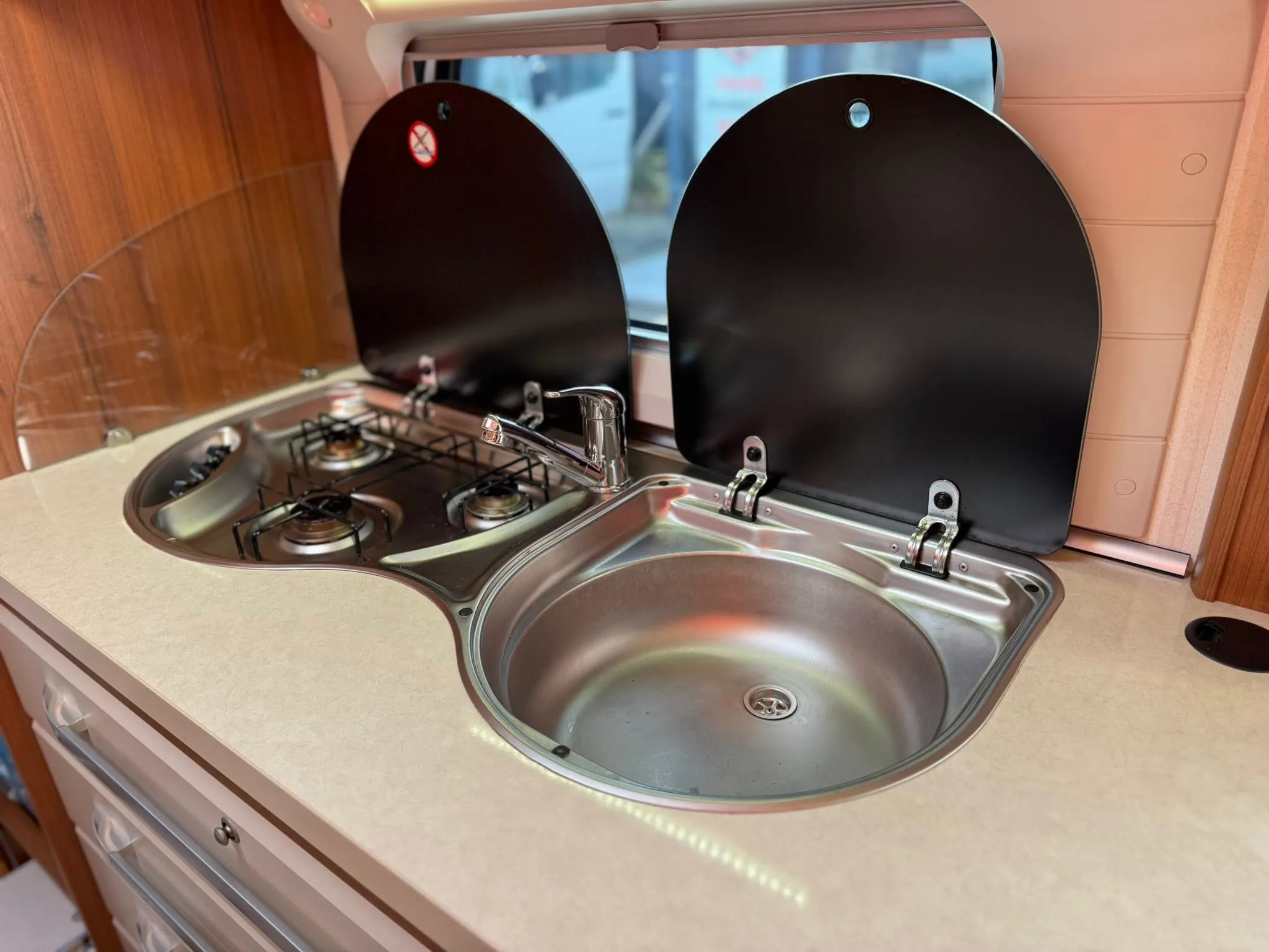 Kuchyňský kout obytného auta se dvoma vařiči a umyvadlem. Moderní design, ideální pro kempaření.