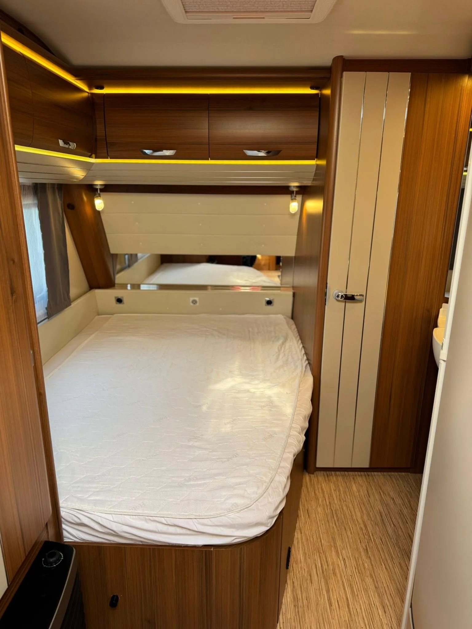 Interiér obytného vozu s moderním designem a prostornou postelí. Komfortní a stylové bydlení na cestách.