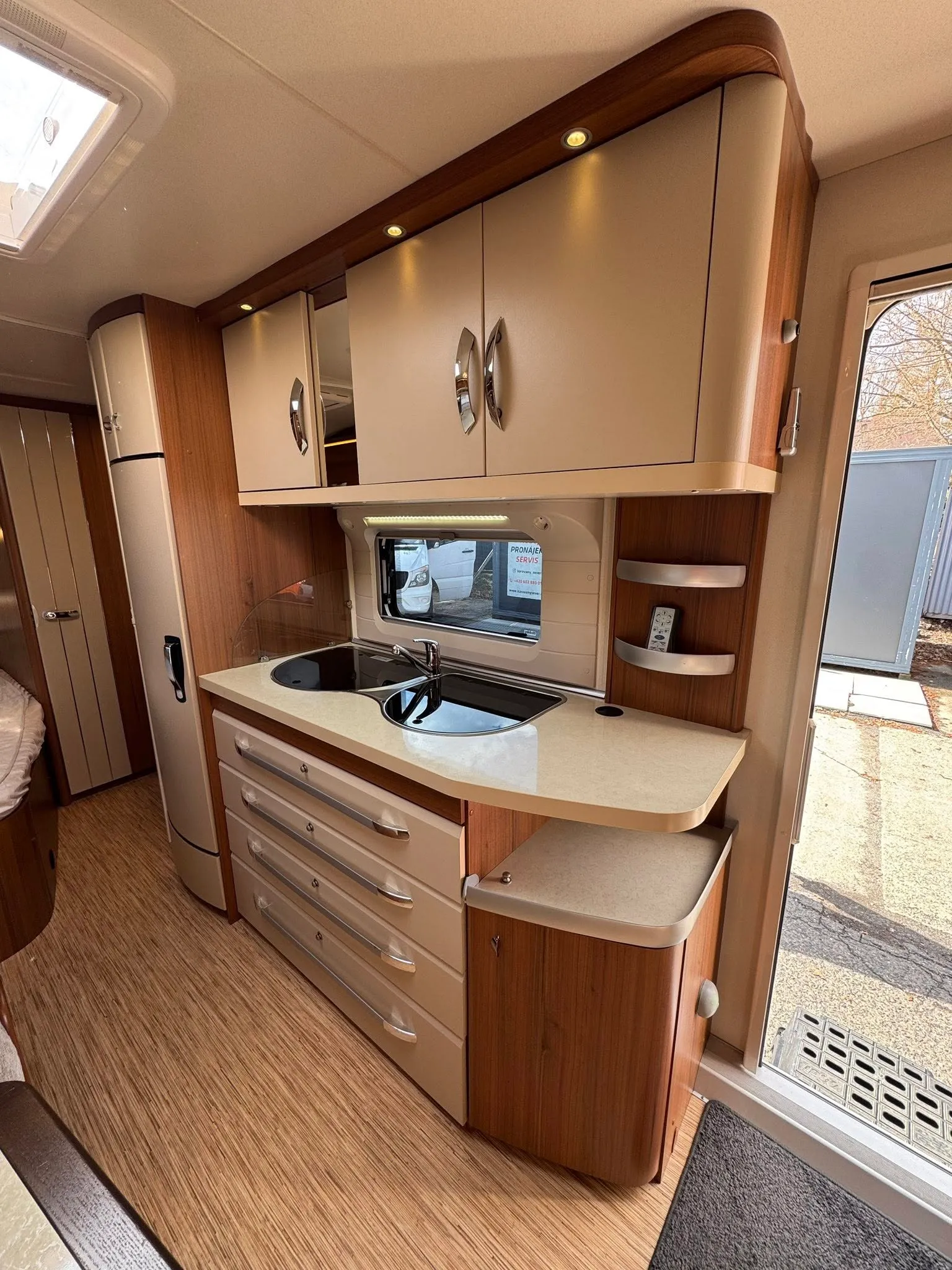 Interiér karavanu s moderními kuchyňskými prvky a úložným prostorem. Vhodný pro pohodlné cestování.