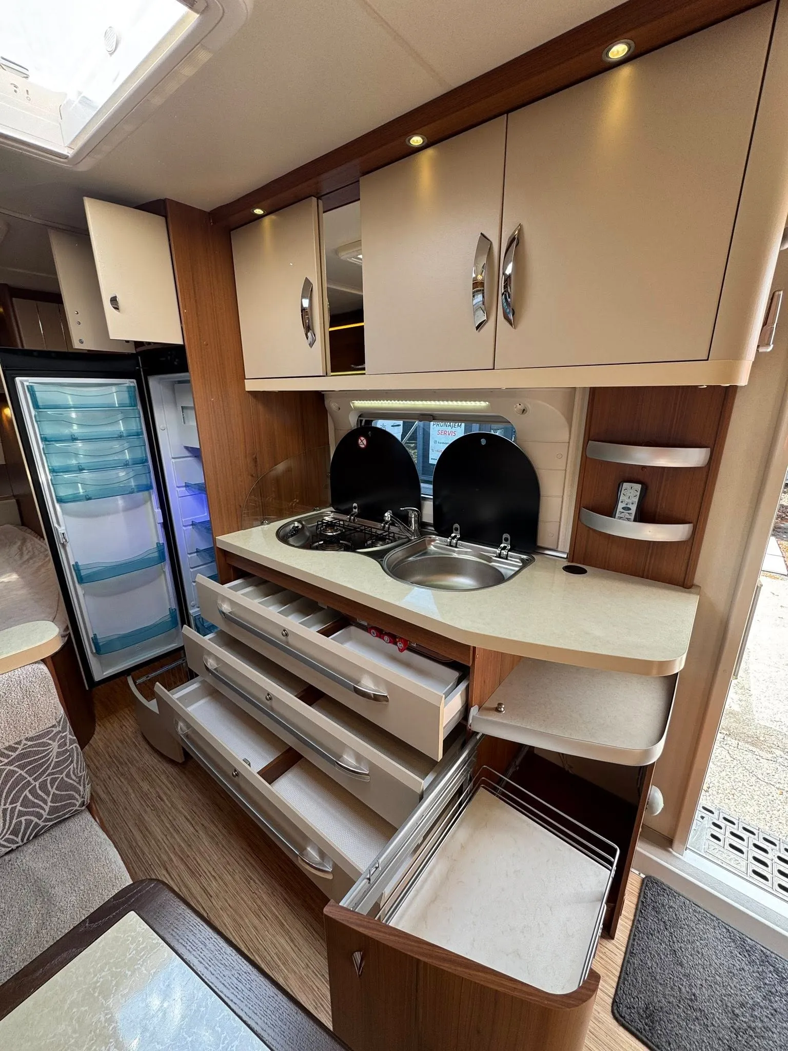 Obrázek interiéru obytného auta s moderní kuchyňkou a dostatkem úložného prostoru. Komfort a funkčnost na prvním místě.