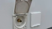 Obrázek zobrazuje vodní přípojku na karavanu s bílým exteriérem.