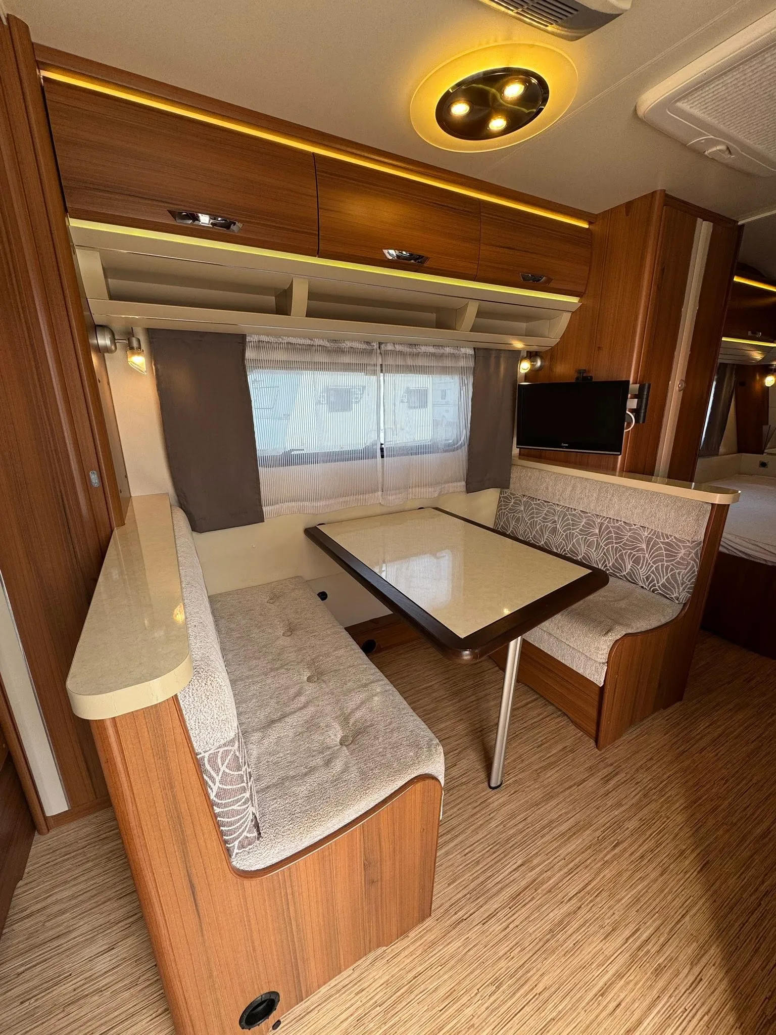 Interiér karavanu s pohodlným sezením a moderním osvětlením. Ideální pro pohodové cestování.