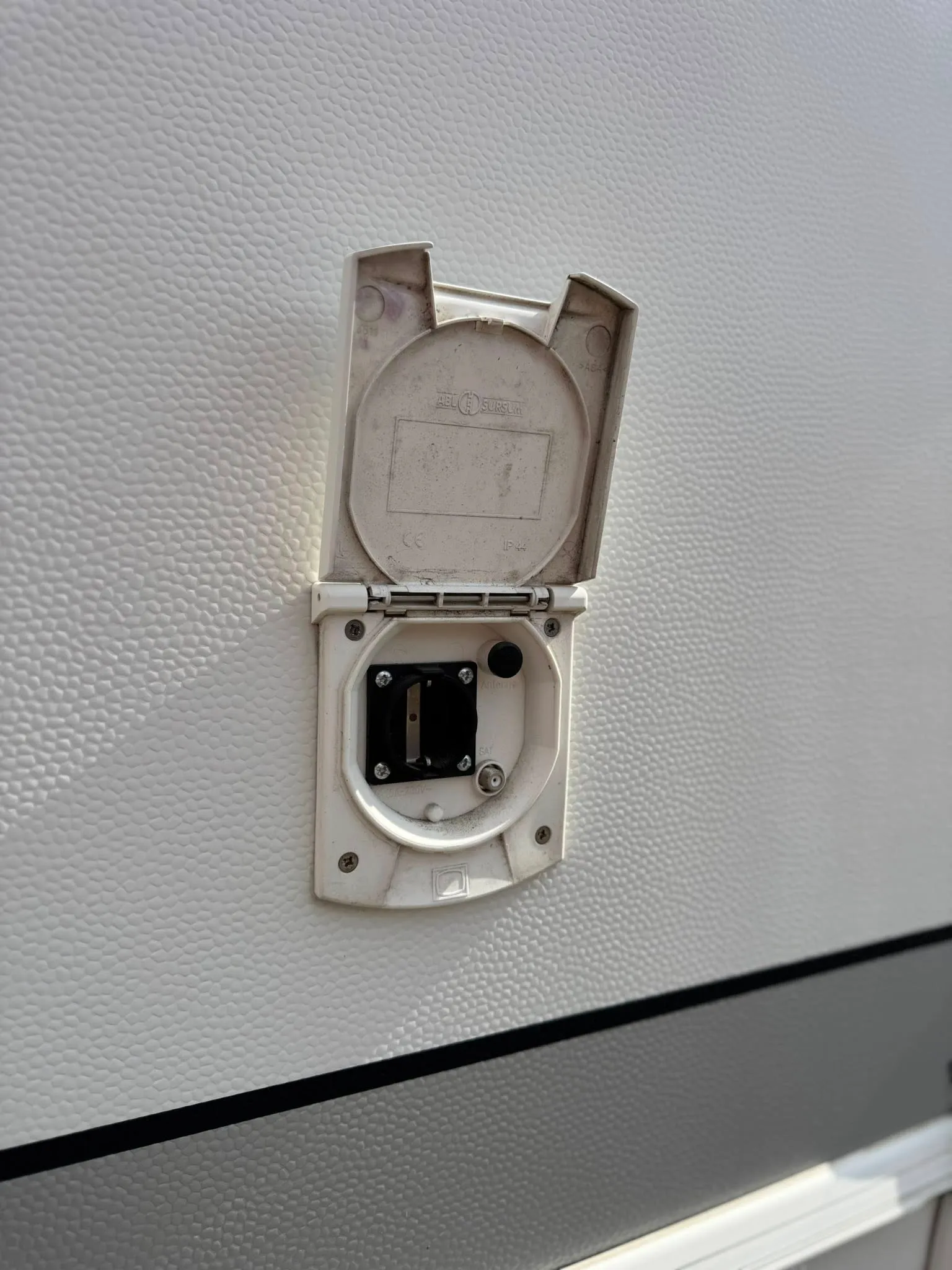 Obrázek ukazuje elektrickou zásuvku na karavanu, ideální pro připojení k externímu napájení.