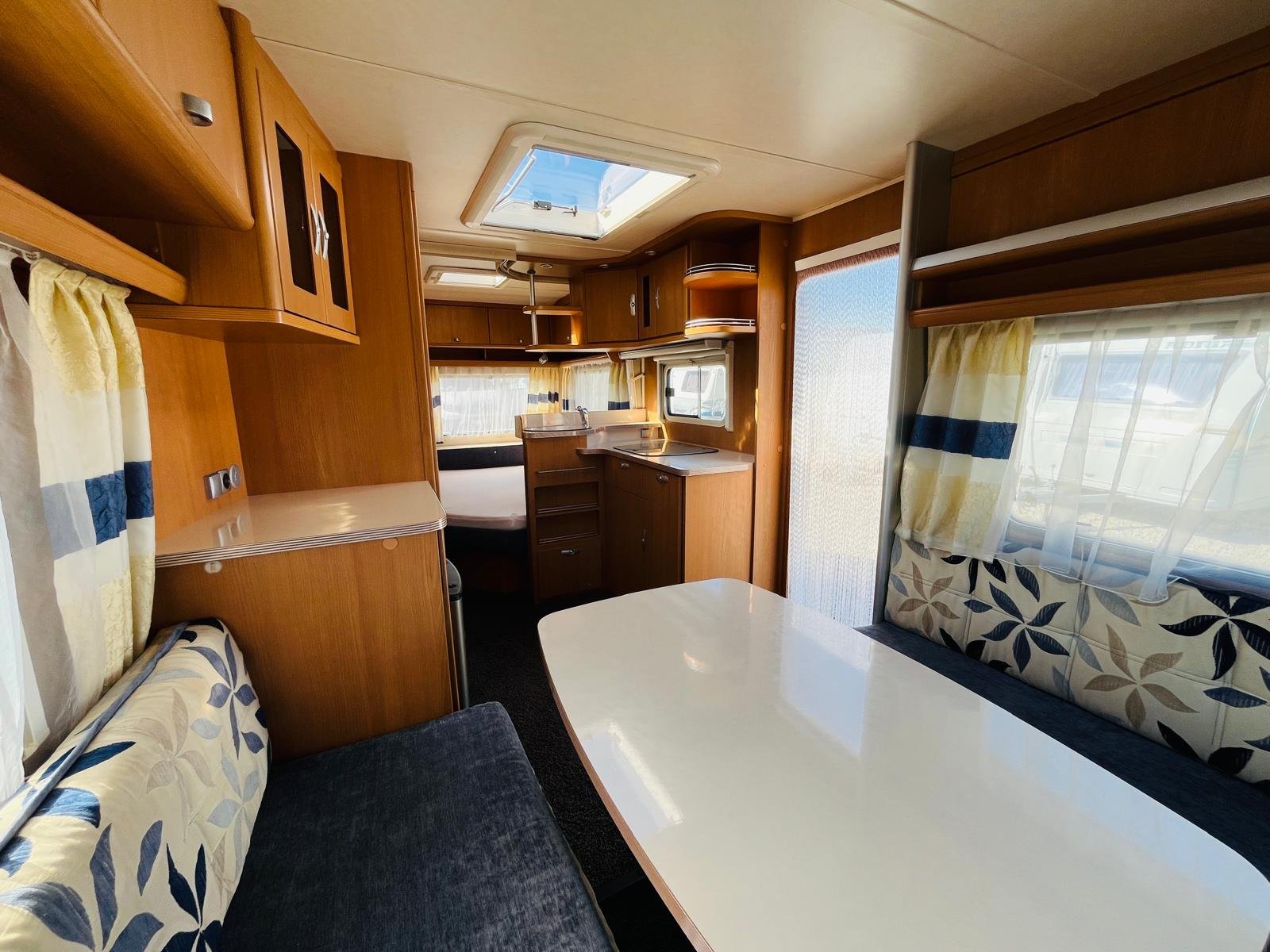 Interiér karavanu s prostorným sezením a kuchyňským koutem. Ideální na cestování a pohodlný pobyt.