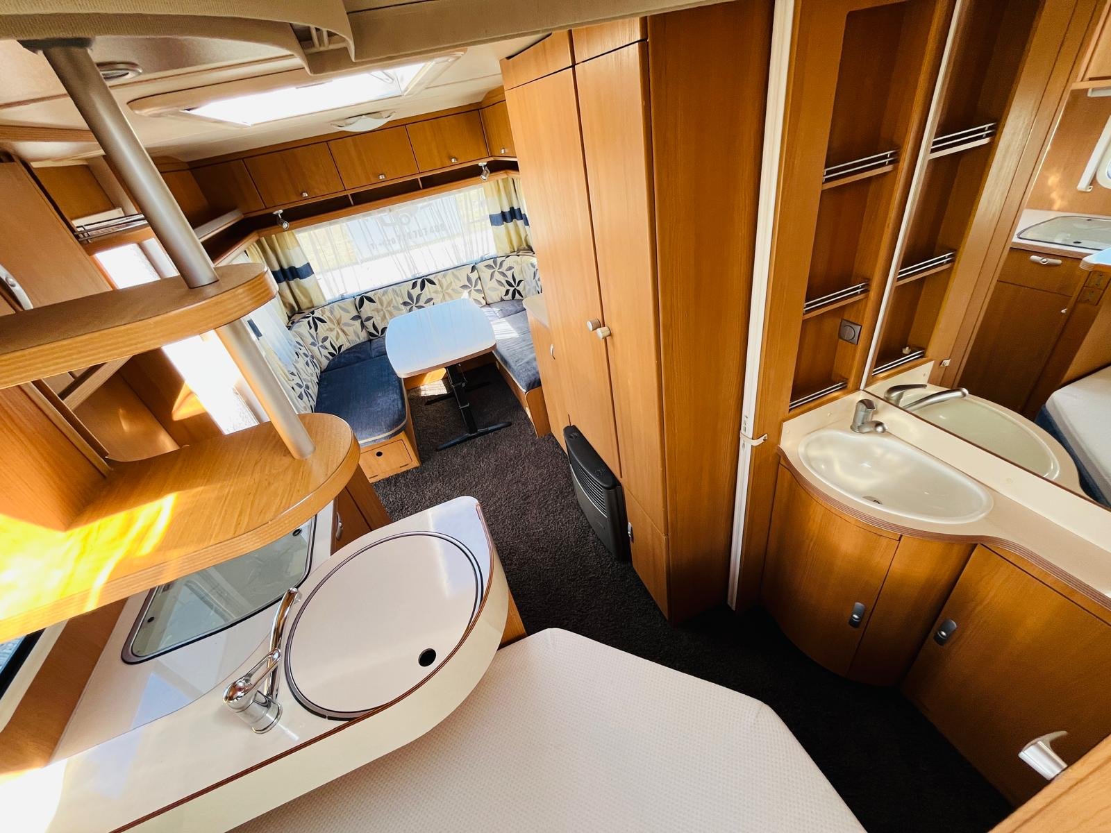 Obrázek interiéru karavanu s dřevěnými prvky a prostornou kuchyní. Vhodný pro pohodlné cestování.