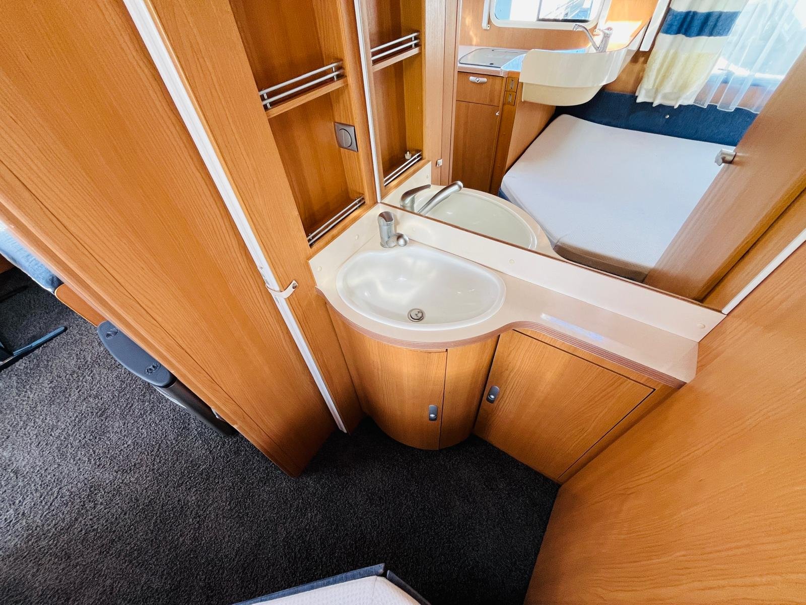 Koupelna v karavanu s dřezem a útulným interiérem vhodná pro pohodlné cestování.