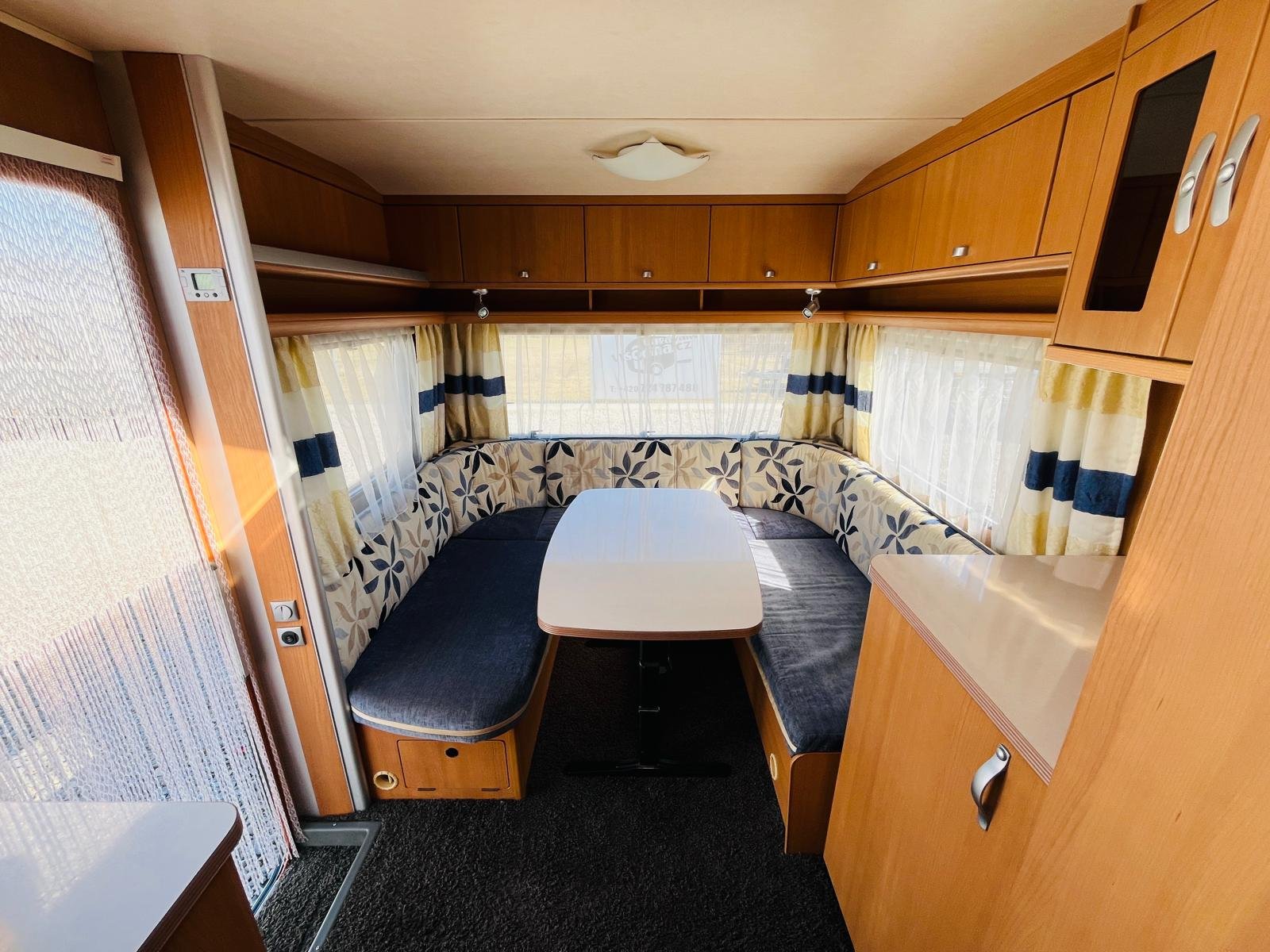 Stylový karavan s prostornou sedací soupravou a jídelním stolem, ideální pro pohodové cestování.