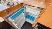 Obrázek interiéru obytného vozu s lednicí značky Dometic a pohodlným sezením. Ideální pro cestování.