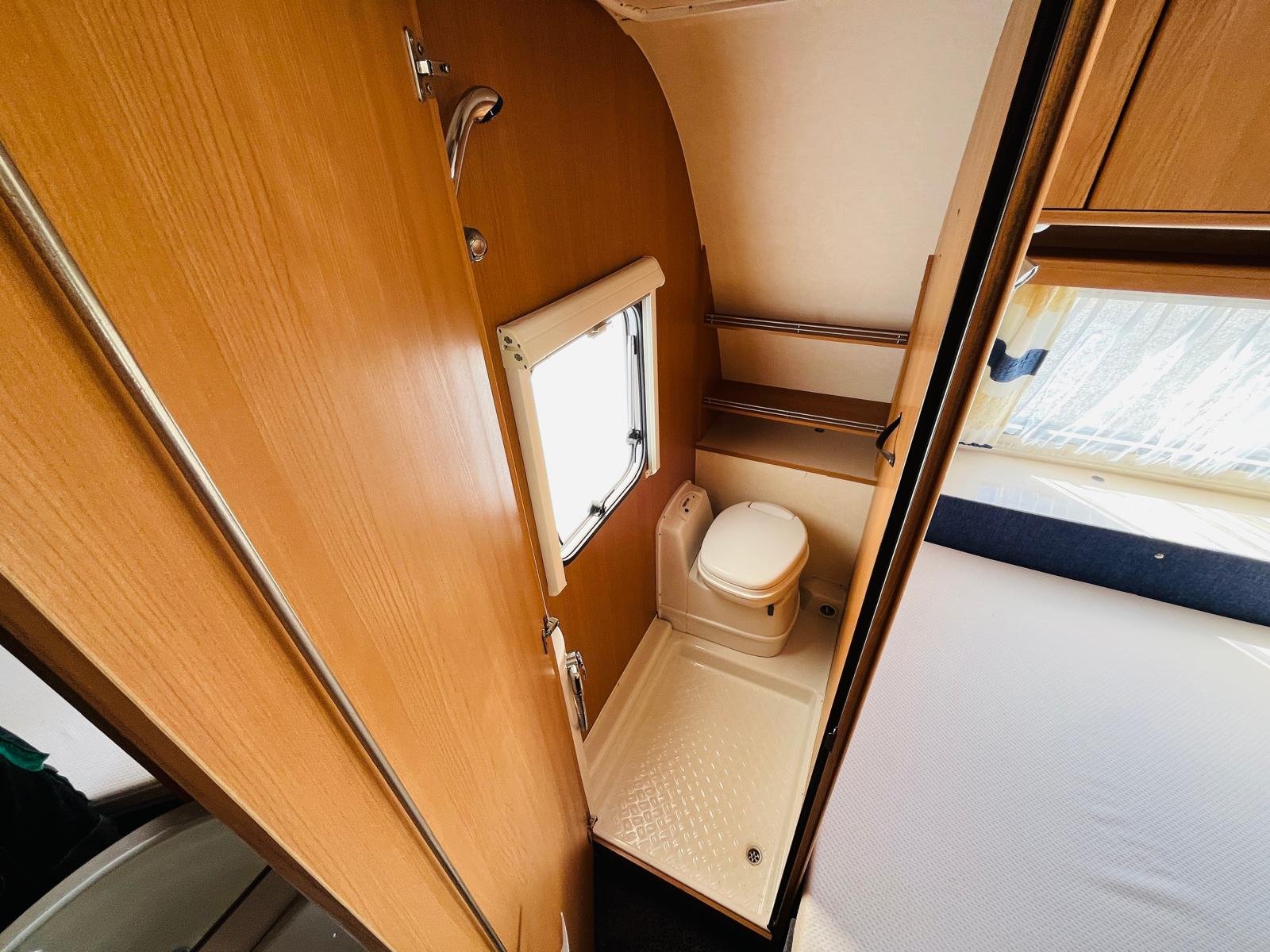 Interiér karavanu se sprchou a toaletou, ideální pro pohodlné cestování.