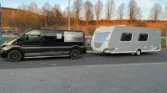 Obytné auto a karavan stojí na parkovišti, připravené na dobrodružství v přírodě. Modely nejsou viditelné.