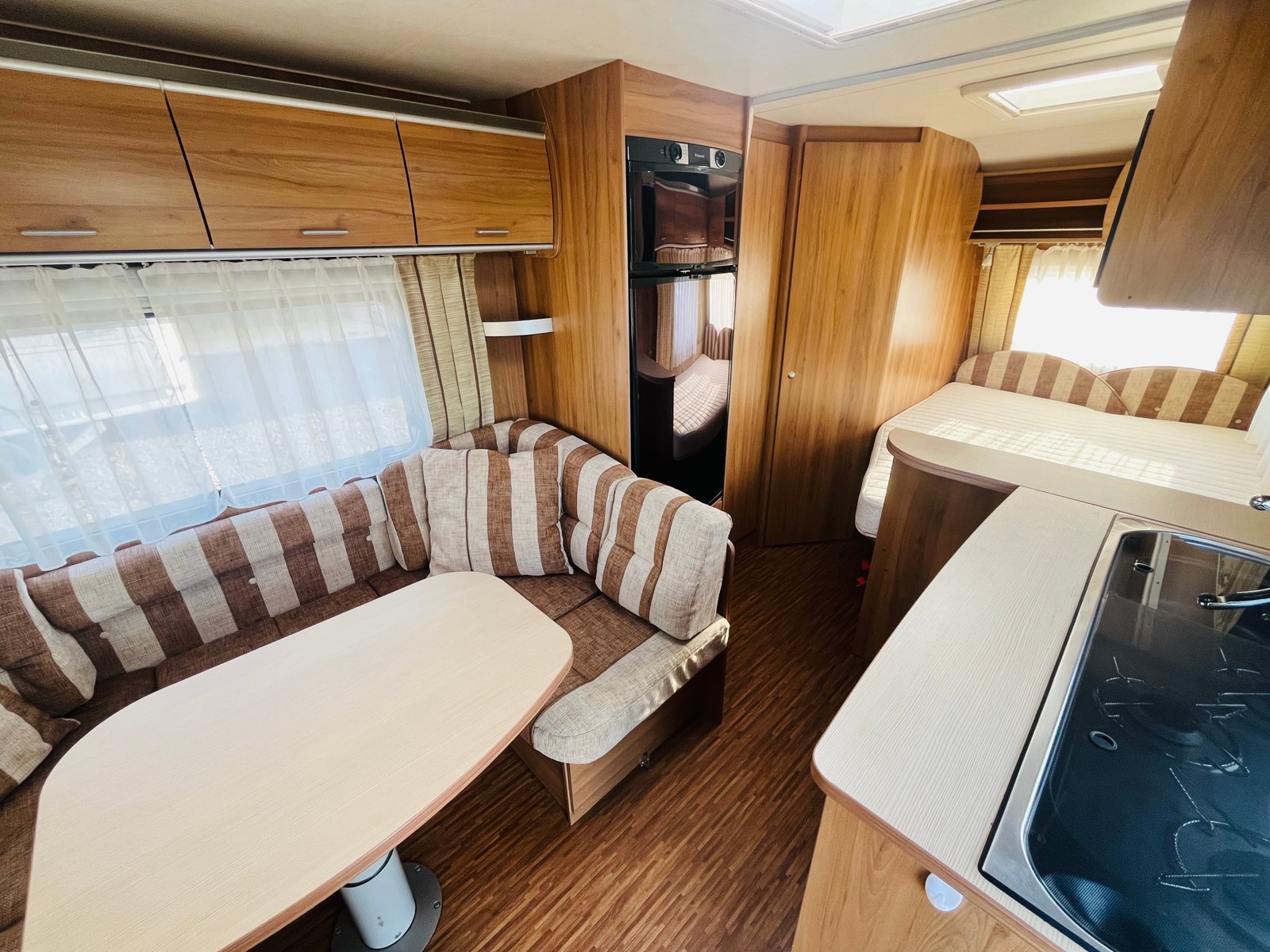 Interiér moderního karavanu s pohodlným sezením a kuchyňským koutem. Ideální pro cestování a odpočinek.