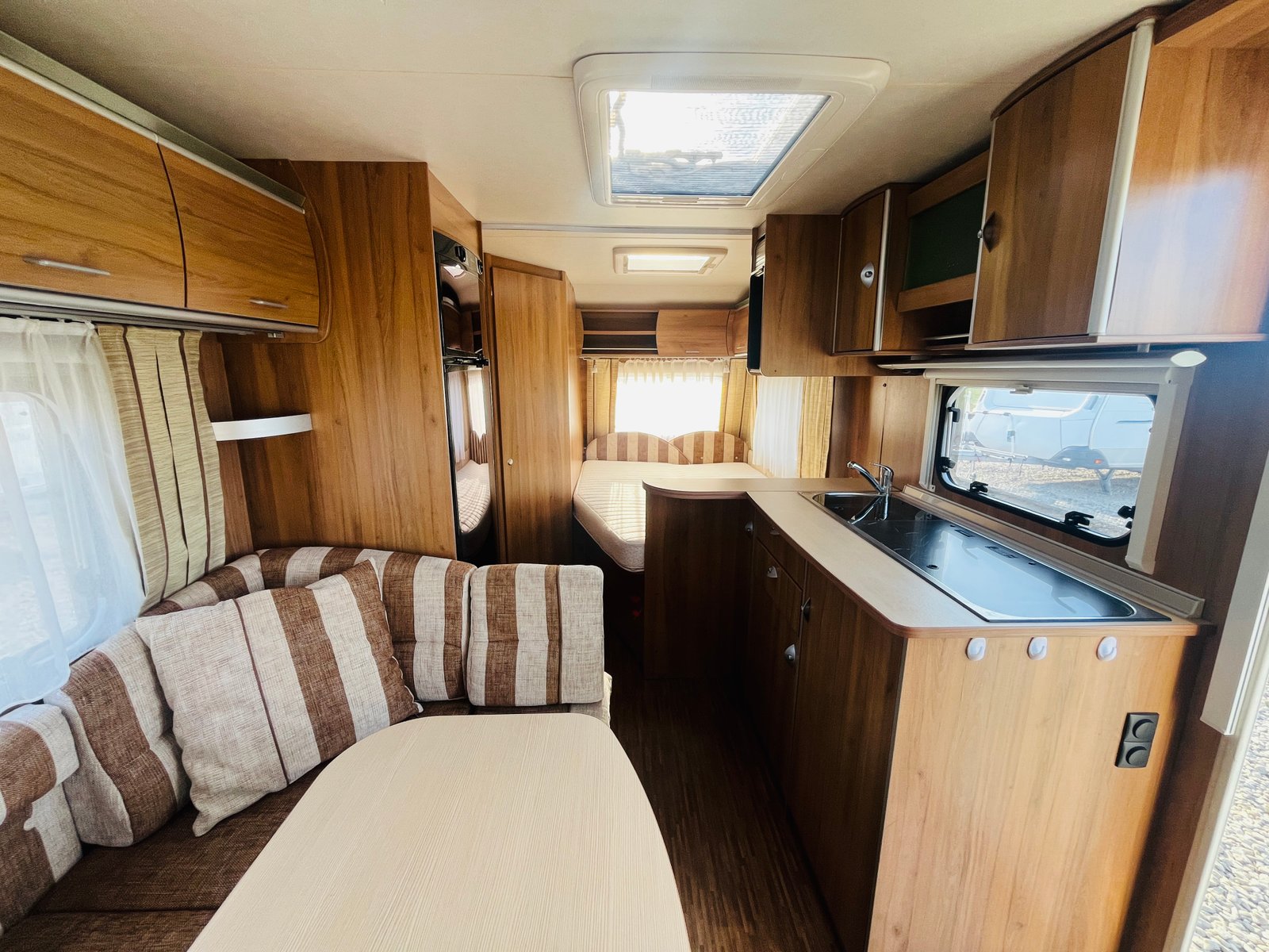 Interiér karavanu s dřevěným obložením a pohodlným sezením. Ideální pro pohodlné cestování.