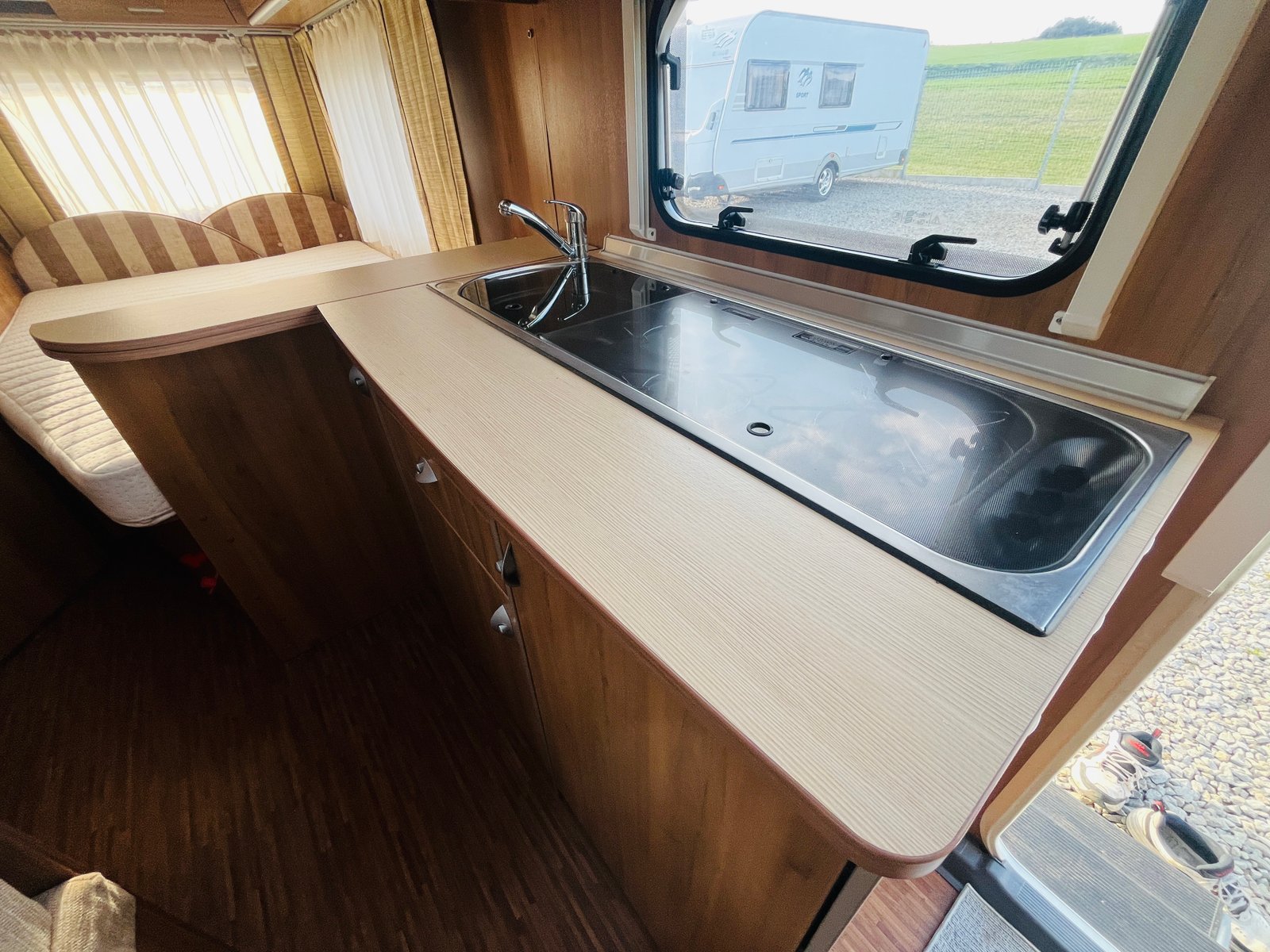 Interiér karavanu s kuchyňským koutem a lůžkem. Ideální pro pohodlné cestování a kempování.