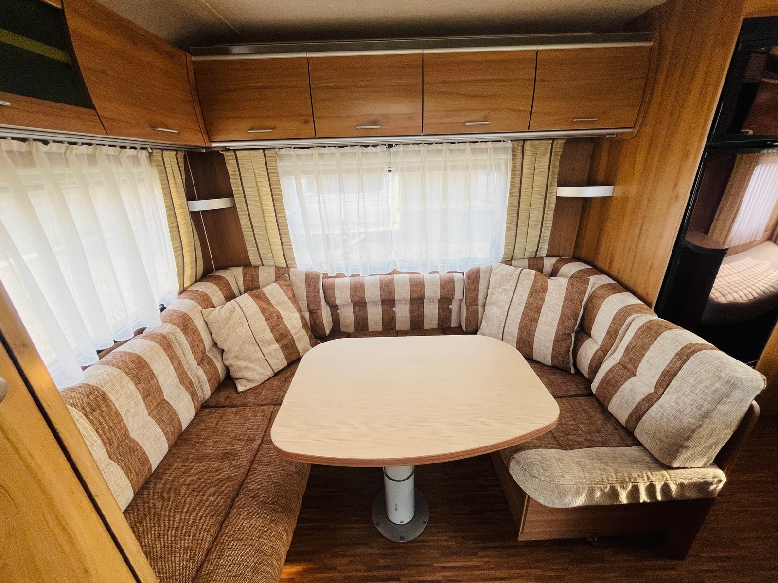 Obrázek interiéru karavanu s pohodlným posezením a stolem. Ideální pro rodinné výlety a odpočinek.
