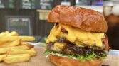 Obrázek ukazuje burger s chedarem a hranolky, ideální pro milovníky dobrého jídla.