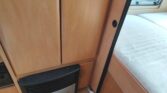 Obrázek interiéru karavanu s dřevěným nábytkem a topením, ideální pro pohodlné cestování.