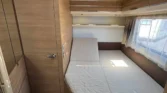 Interiér obytného auta s prostornou postelí a moderním designem. Ideální pro pohodlné cestování.