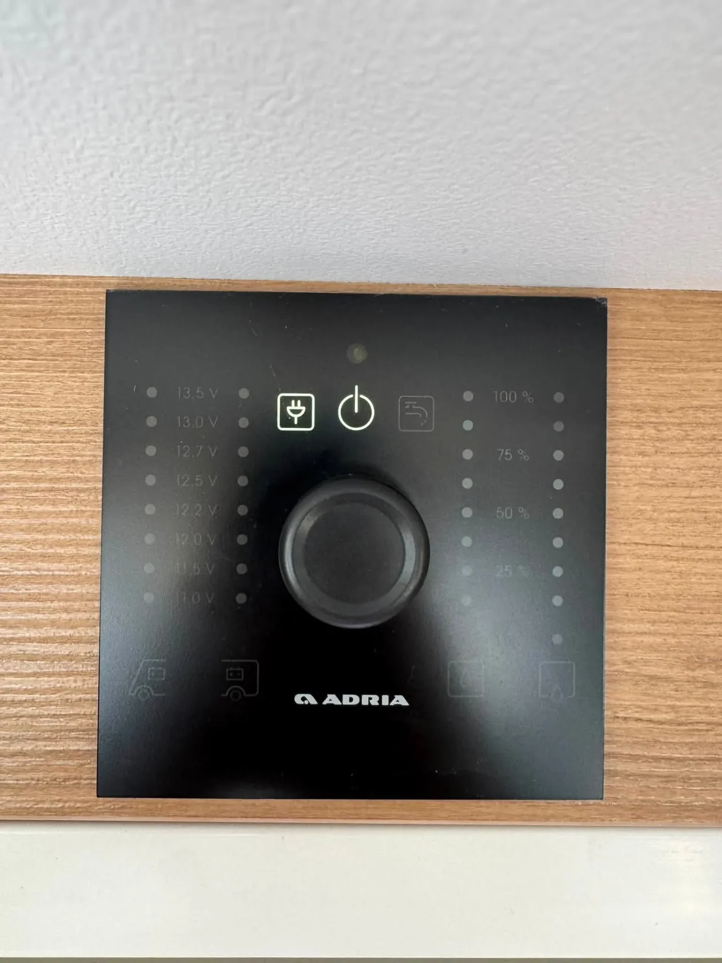 Obrázek ukazuje ovládací panel značky Adria, určený pro obyvatele obytného auta nebo karavanu.