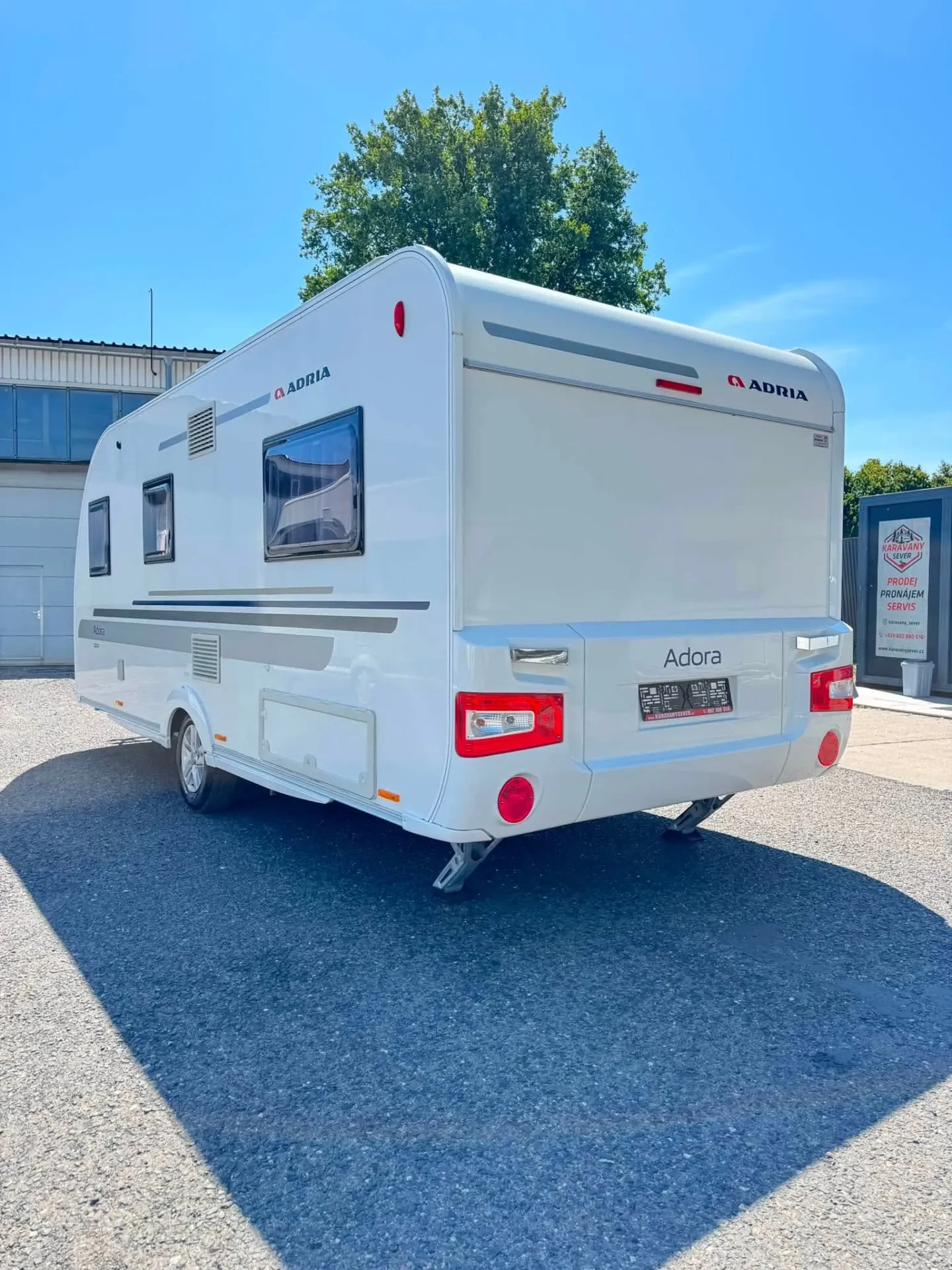 Karavan Adria Adora v bílém provedení, ideální pro pohodlné cestování a dovolenou.