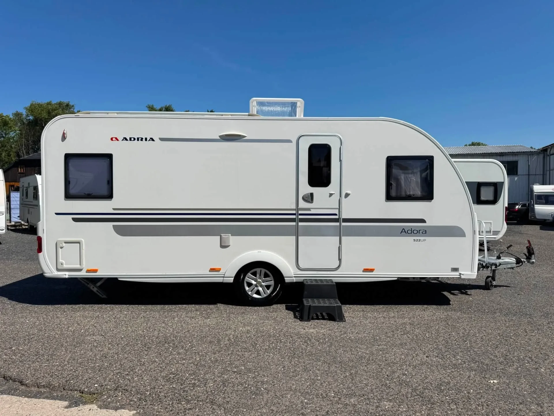 Karavan Adria Adora S522 UP v elegantním bílém designu, ideální pro komfortní cestování.