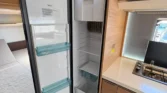 Interiér obytného vozu s prostorným chladničkou a kuchyňským koutem. Idealní pro kempování a cestování.