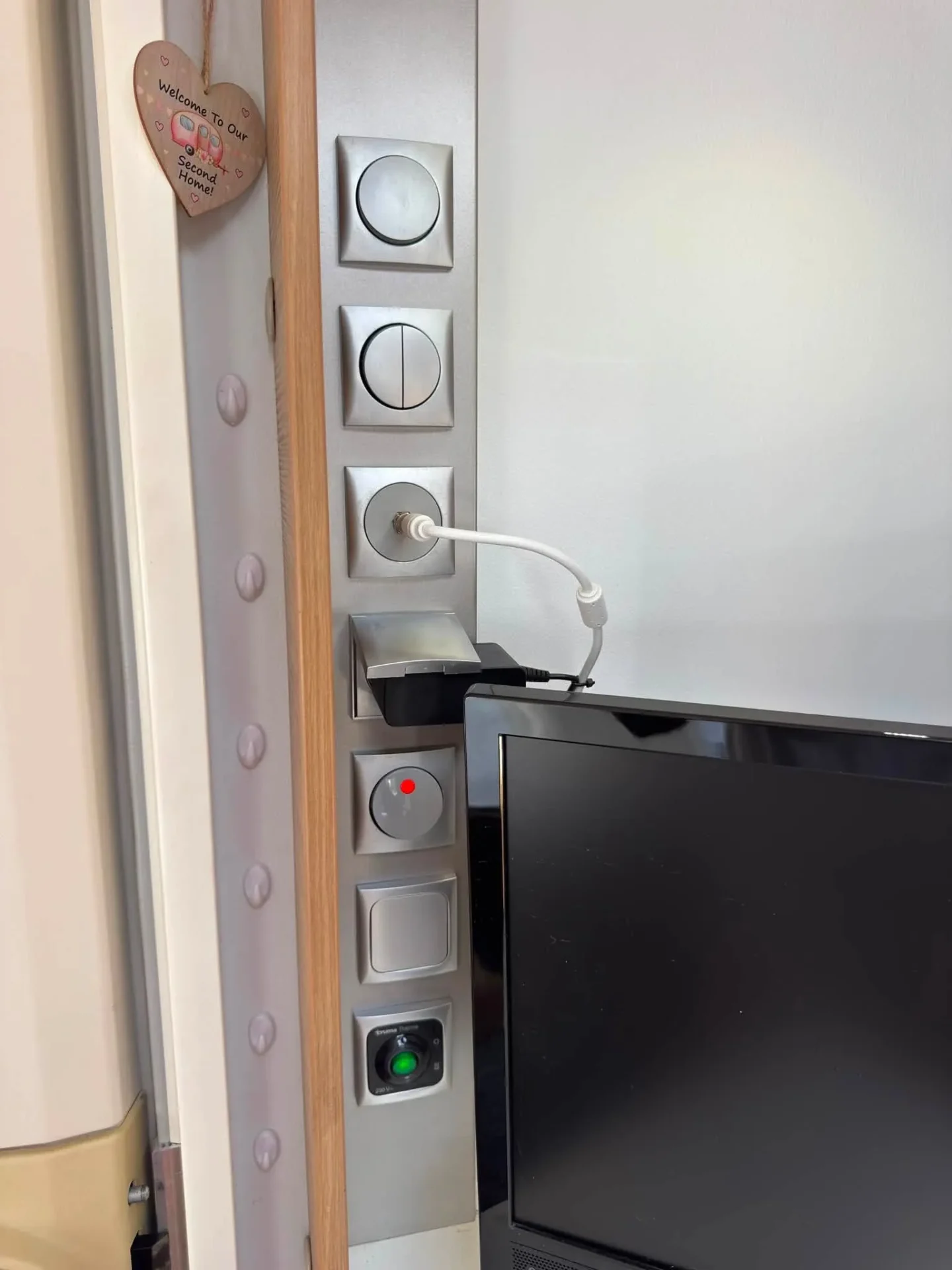 Na obrázku je moderní interiér obytného auta, s ovládacími prvky a televizorem. Komfortní a praktický design.
